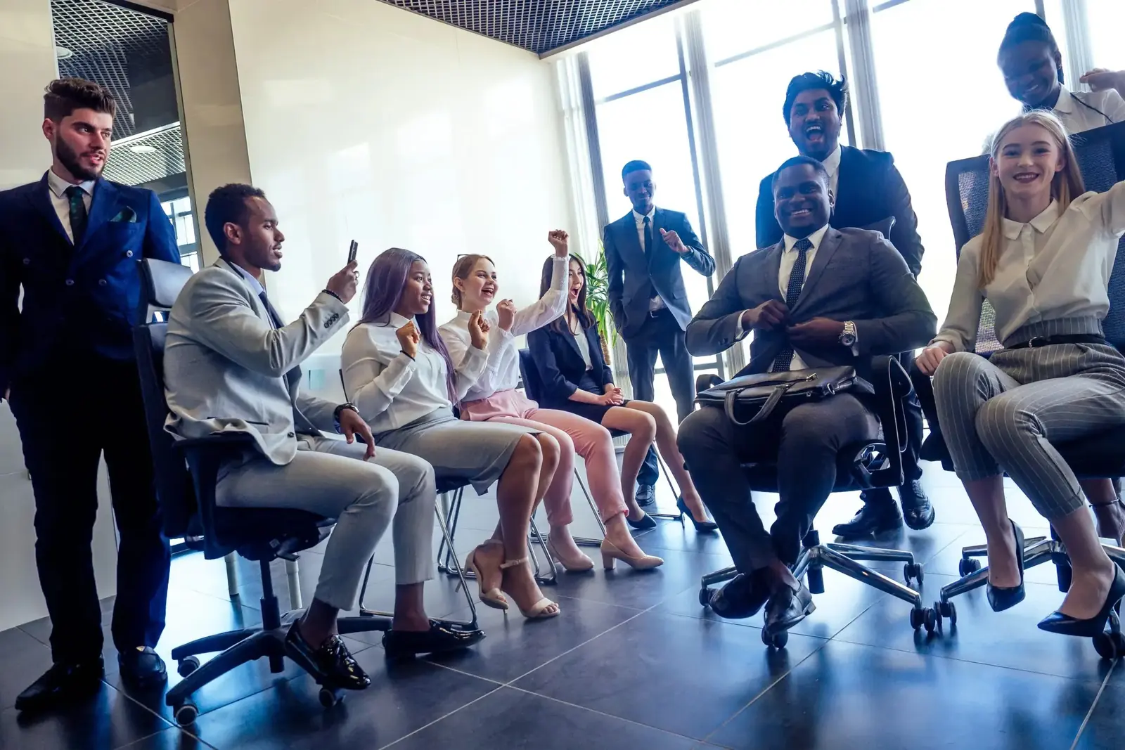 Une femme et un homme d'affaires complices sur des chaises de bureau devant une fenêtre panoramique